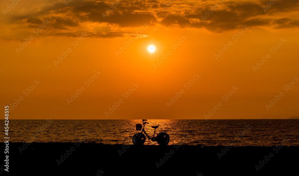 silhouette bicycle parking on sand beach near the sea with sunset sky background.