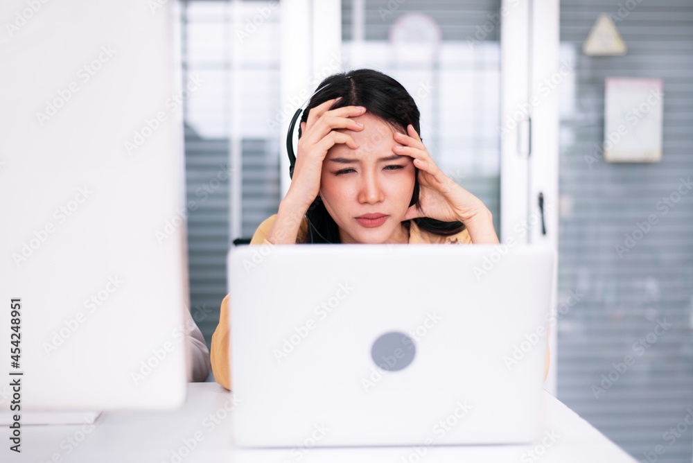 Headache asian woman customer service agent during working at call center service Headache asian woman customer service agent during working at call center service
