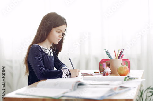 Little girl sitting on a table with books