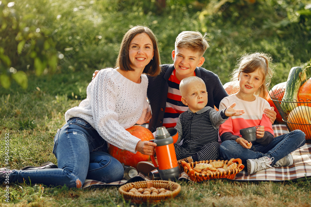 Big family sitting on a garden near many pumpkins