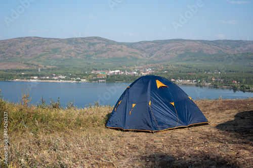 Blue tent on the lake shore and mountains on background