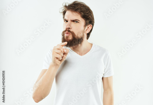 emotional man in a white t-shirt hand gestures anger light background