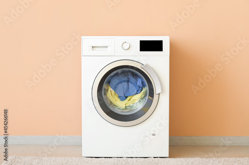 Modern washing machine with laundry near color wall © Pixel-Shot