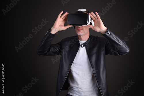 Man in leather jacket interacting with vr glasses black background