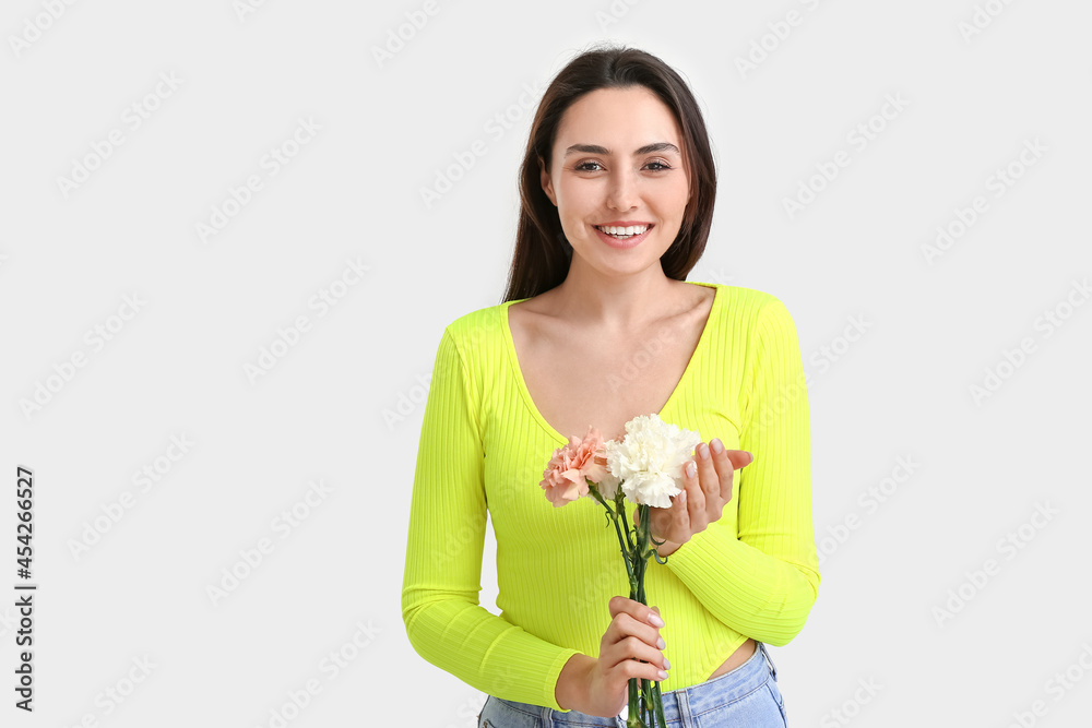 Young woman with beautiful carnation flowers on light background Young woman with beautiful carnation flowers on light background