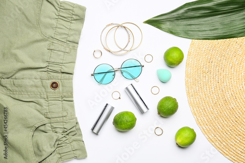 Composition with female accessories, clothes and limes on white background, closeup