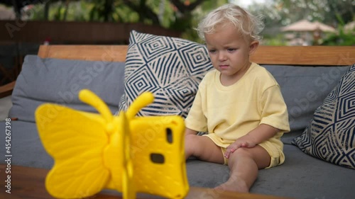 Toddler child watching a cartoon on a digital tabled in a kid -riendly yellow butterfly case photo