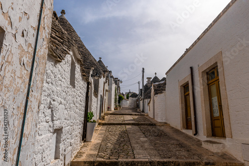 Biegnąca w górę wąska uliczka między Trulli - charakterystycznymi małymi domkami ze stożkowatymi kamiennymi dachami. Alberobello, Puglia, Włochy
