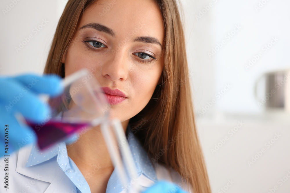 Female chemist holds test tube of glass in his hand overflows a liquid Female chemist holds test tube of glass in his hand overflows a liquid