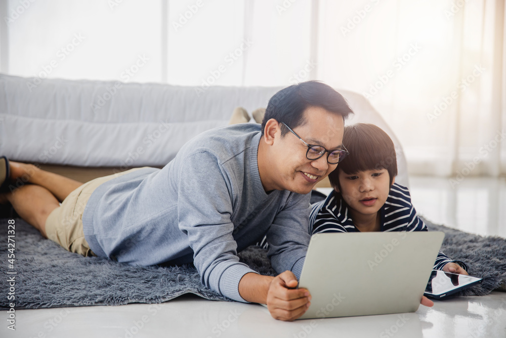 Father and son with laptop and tablet next to his little son at home