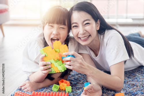 Enjoy happy love Asian family mother and little cute girl smiling playing with toy building or construction toys at home