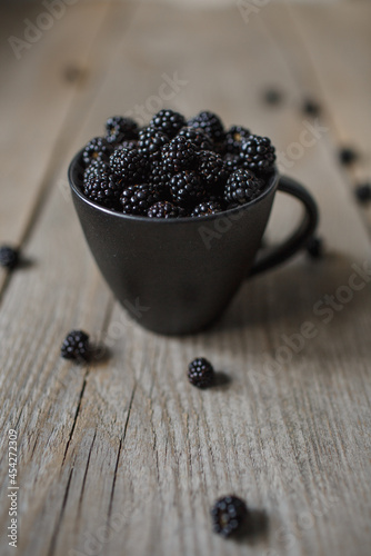 blackberries in a black glass on a wooden background