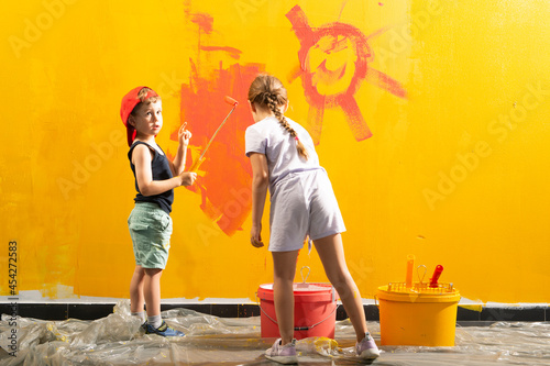 A boy and a girl paints a wall at home photo