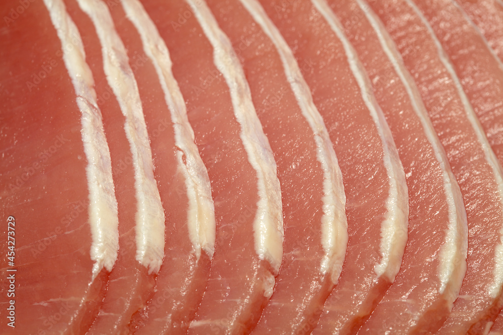 Raw marinated pork lean loin cut into thin sliced with almost all of the fat trimmed 
