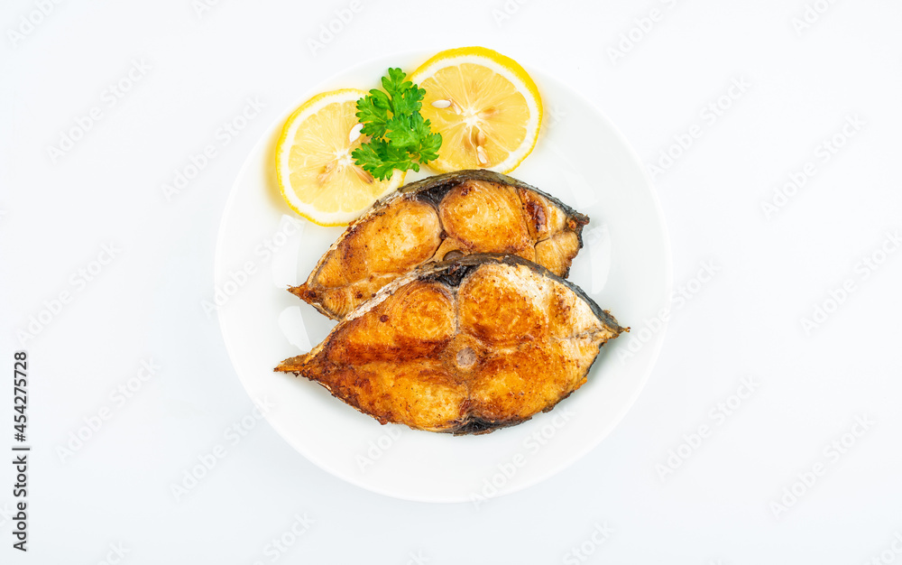 Pan-fried mackerel pieces on a plate on white background