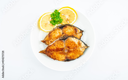 Pan-fried mackerel pieces on a plate on white background