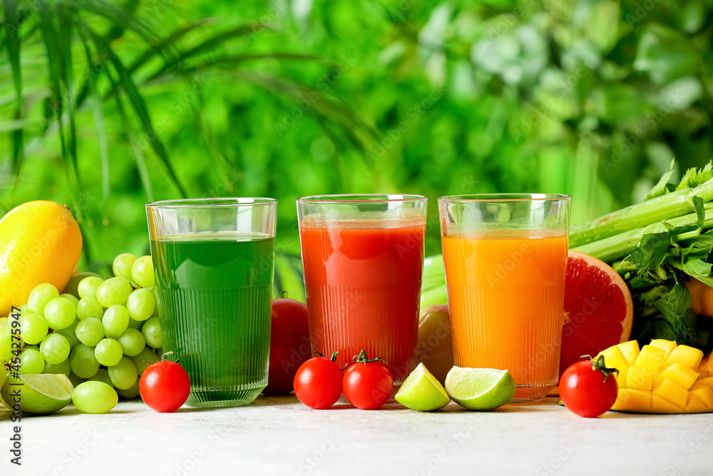 Glasses with healthy juice, fruits and vegetables on table outdoors, closeup Glasses with healthy juice, fruits and vegetables on table outdoors, closeup