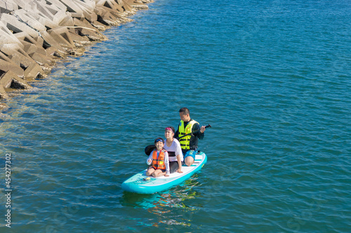 夏の海でサップボードを遊んでいる親子の姿