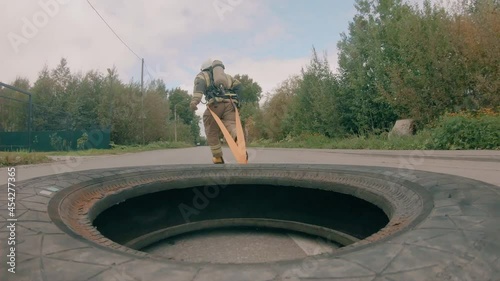 The fireman runs along the road from side to side and pulls the tire of the car behind him. Physical training of firefighters. Difficult physical exercise.