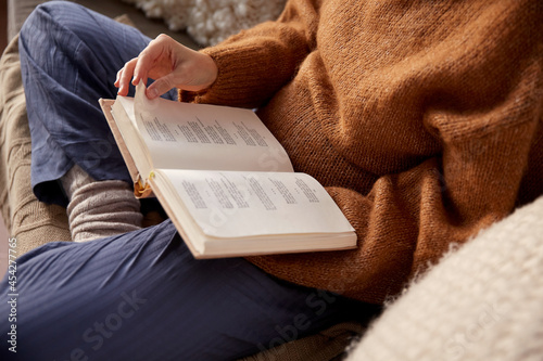 people, season and leisure concept - close up of woman in warm sweater reading book at home photo