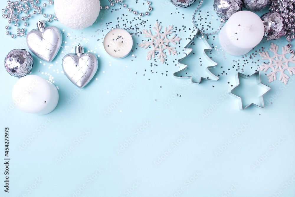 Obraz premium Silver and white christmas decorations on a blue background. Top of view