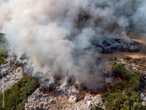 Top-down view of burning wastes at trash site exhaling much thick smoke polluting the air. Environmental pollution