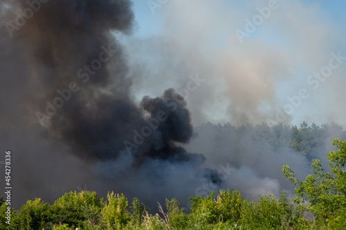 Black toxic smoke from burning plastic in the countryside. Garbage dump in fire polluting the air with harmful gases