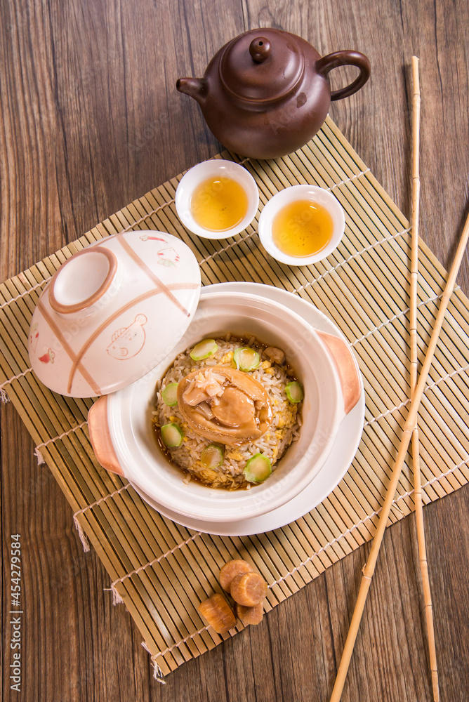 chinese wok egg fried rice with whole abalone in hot clay pot on wood background asian halal banquet menu