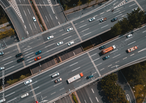 Top up aerial drone view of elevated road and traffic junctions in Chinese metropolis city during sunny day golden hour. Modern construction design of traffic ways to avoid traffic jams. Few vehicles.