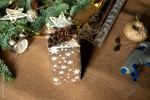 Process of wrapping gift presents with ornaments made of natural materials, top view, flat lay
