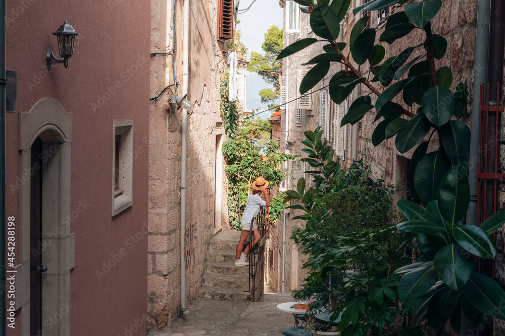 Girl tourist walking through ancient narrow street on a beautiful summer day in Korcula, Croatia