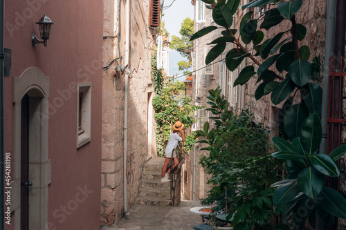 Girl tourist walking through ancient narrow street on a beautiful summer day in Korcula, Croatia