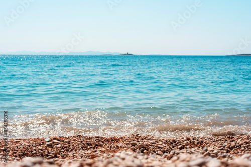 Fototapeta Naklejka Na Ścianę i Meble -  Beautiful pebble beach and blue sea with islands. Shallow depth of field