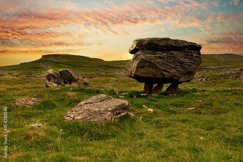 A dramatic sunrise with yellow and pink clouds  framing a perched erratic, part of the Norber erratics in the Yorkshire Dales photo