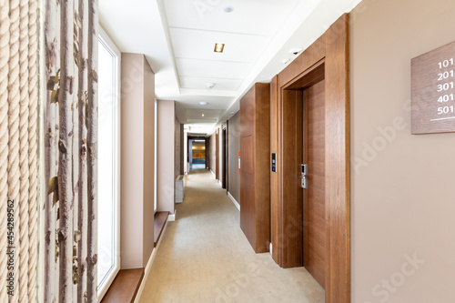 Interior of a carpeted hotel corridor with windows