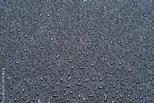 Dark background with large drops of water on fresh asphalt. Road surface wet from rain. Black sad backdrop