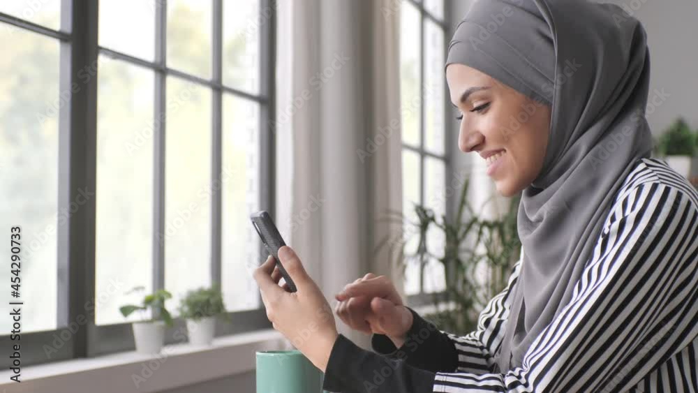 arab young woman in hijab using smart phone mobile at the cafe,connected muslim girl sits at the table holding smartphone browsing internet social media network arab young woman in hijab using smart phone mobile at the cafe,connected muslim girl sits at the table holding smartphone browsing internet social media network