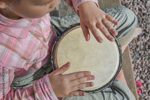 the girl child with a djembe drum outdoor on the porch of the house photo without processing