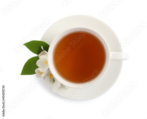 Cup of aromatic jasmine tea and fresh flowers on white background, top view