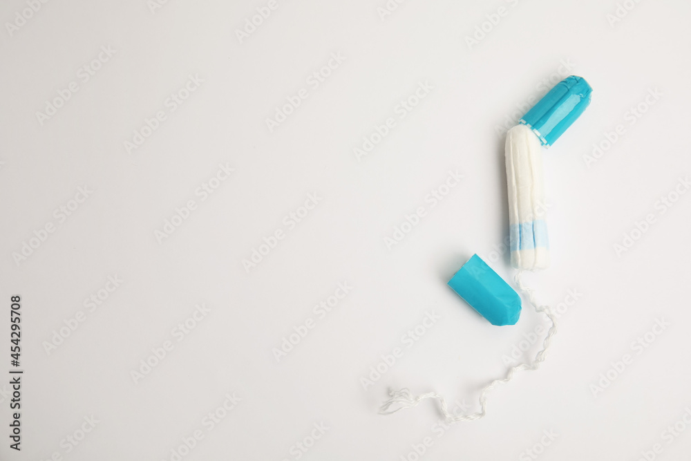 Tampon with package on light background, flat lay. Space for text Tampon with package on light background, flat lay. Space for text