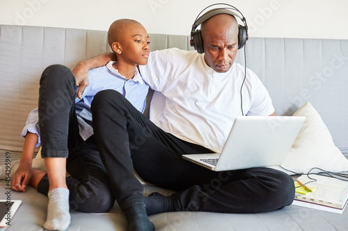 Vater und Sohn auf dem Sofa am Laptop PC im Home Office