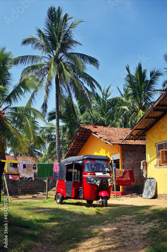 Tuk tuk taxi in Sri Lanka. Typical vehicle parked in the garden. Red tuk-tuk car.