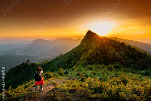 Woman with backpack from behind and beautiful Landscape of mountain with sunset in Chiang Rai, Thailand photo