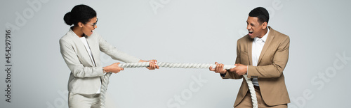 businessman and businesswoman pulling rope isolated on grey, banner