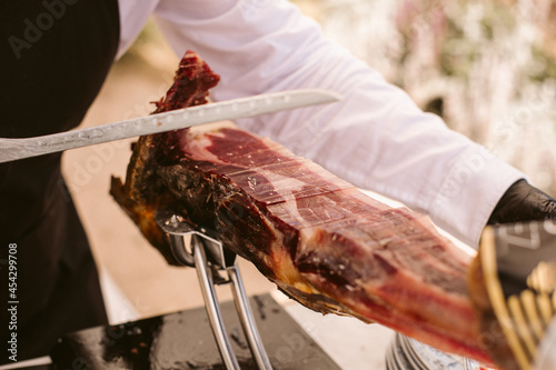 Iberian ham cutter. Traditional spanish jamon serrano pata negra. Professional cutter cutting delicious Iberian ham.