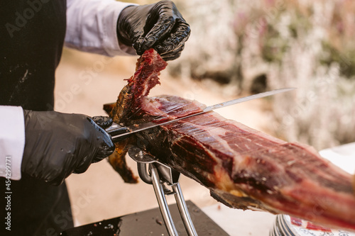 Iberian ham cutter. Traditional spanish jamon serrano pata negra. Professional cutter cutting delicious Iberian ham.