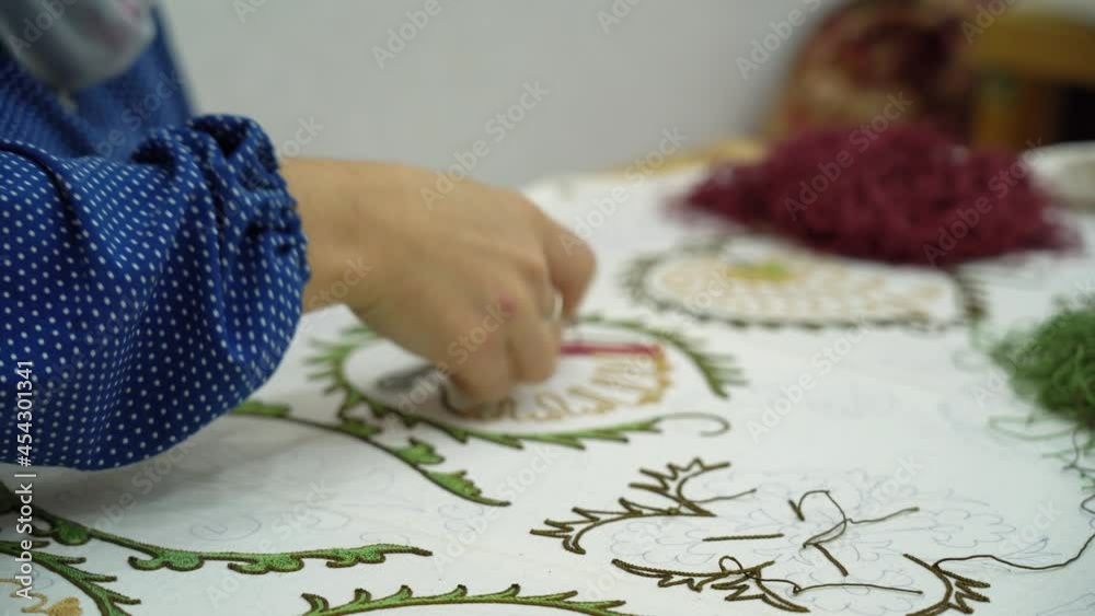 Young artisan girl works on national Uzbek embroidery. Creating an ornament in a traditional style. Historical art Young artisan girl works on national Uzbek embroidery. Creating an ornament in a traditional style. Historical art