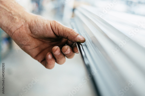 Young male worker assembling products in modern PVC and aluminum doors and windows production factory. Extreme close up shot of worker's hands.