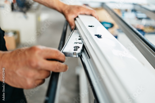 Young male worker assembling products in modern PVC and aluminum doors and windows production factory. Extreme close up shot of worker's hands.