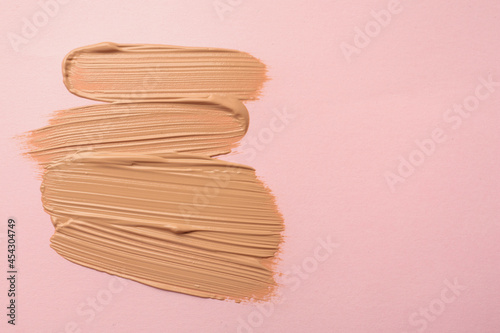 Fotografiet Sample of liquid skin foundation on pink background, top view